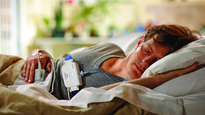 Mies nukkuu s&auml;ngyss&auml; kyljell&auml;&auml;n Philipsin unirekister&ouml;intilaitteen kanssa.