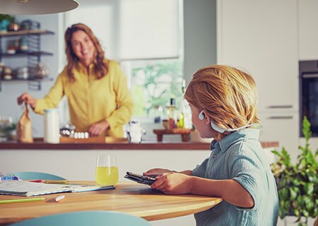 Poika katsomassa videota Philipsin langattomien open-ear-mallisten lasten kuulokkeiden kanssa