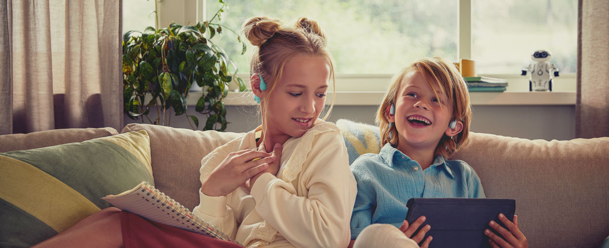 Lapset katsomassa videota Philipsin lapsille tarkoitettujen open-ear-kuulokkeiden kanssa