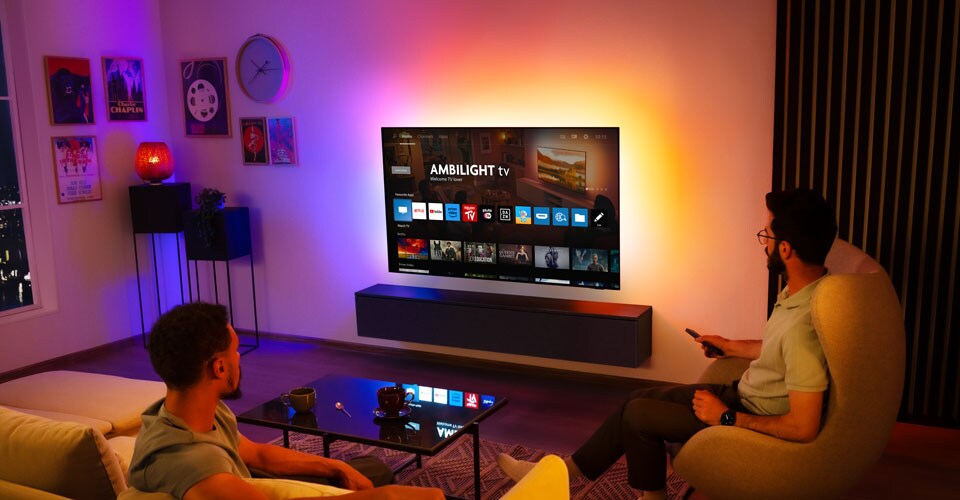 Kaksi miestä katselee seinään kiinnitettyä Ambilight-televisiota olohuoneessa