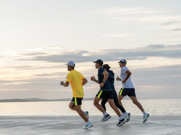 Neljä osallistujaa juoksee yhdessä rannalla.