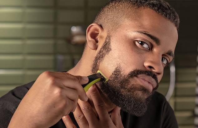 Mies lähikuvassa ajamassa partaansa ja muotoilemassa partaan yhdistyviä pulisonkeja.