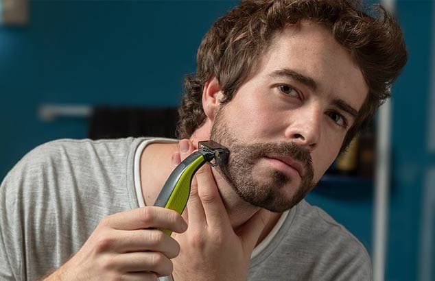 Nuori mies käyttää trimmeriä, jossa on erikoisosa, jota käytetään huolittelemattoman parran trimmaukseen.