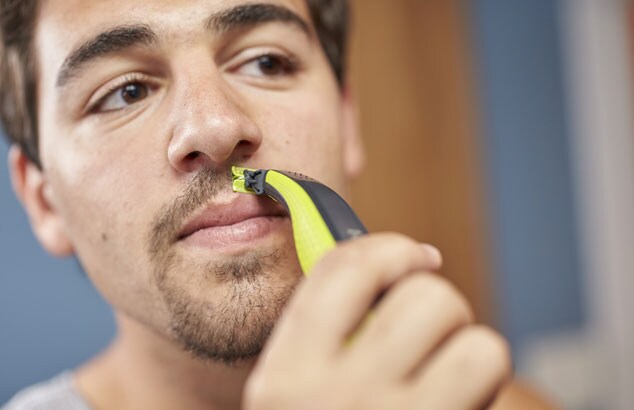Ruskeahiuksinen ja -silmäinen mies käyttää Philips OneBlade -laitetta muotoillakseen pukinpartaa huulten yläpuolelta.