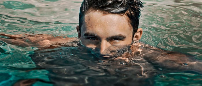 Tummahiuksinen mies ui altaassa