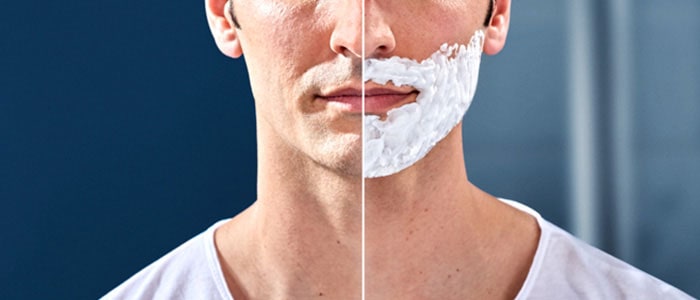 Partansa sileäksi ajaneen miehen kasvojen vasen puoli ja saman miehen oikea puoli, partavaahtoa kasvojen alaosassa.